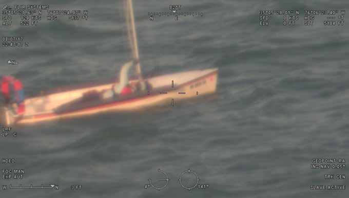 A man in a disabled sailboat waves his arm for help